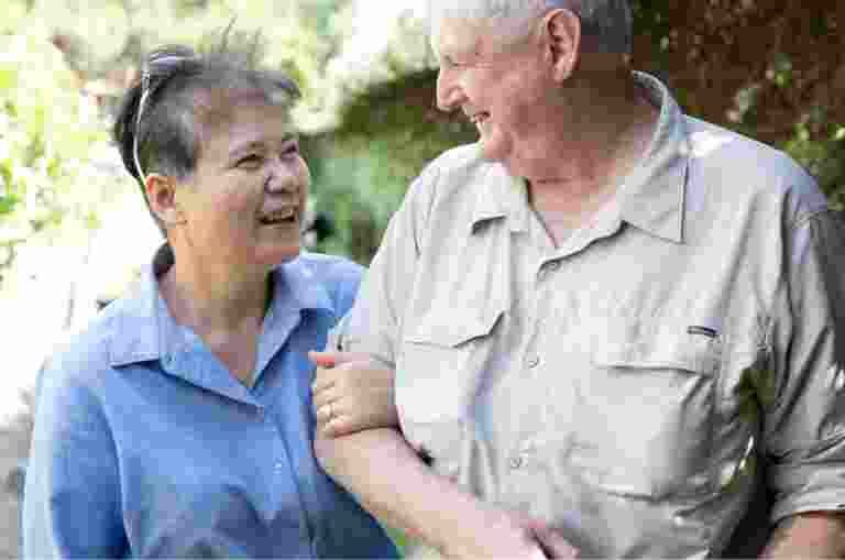 Two people outside looking at each other. One is holding the other at the elbow.