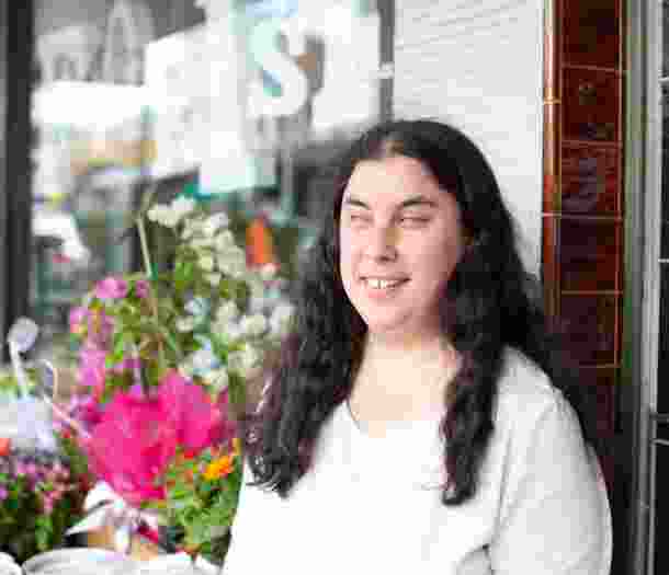 A person standing outside a flower shop with a smile on their face.