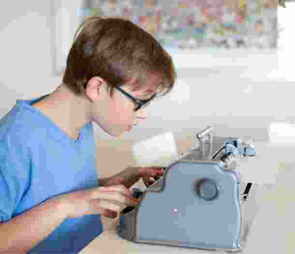 A young child using a braille machine.