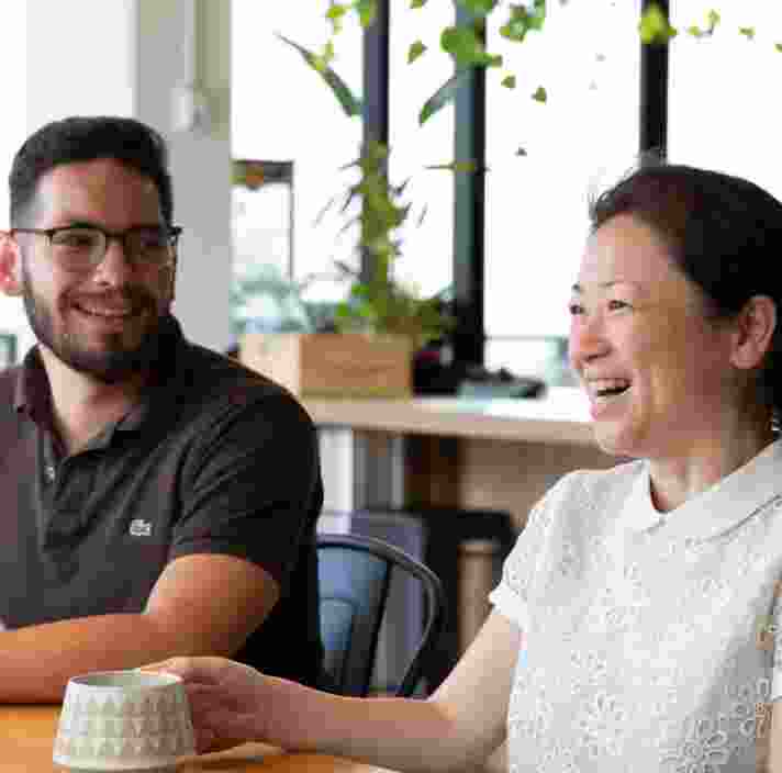 Guide dogs client laughing while sitting drinking coffee with a friend