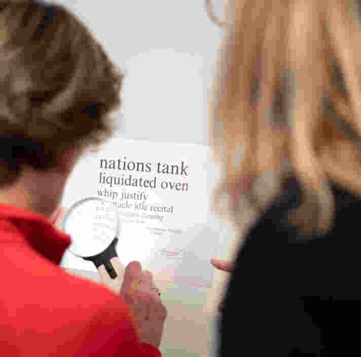 An Orthoptist and a Client using a handheld magnifier.